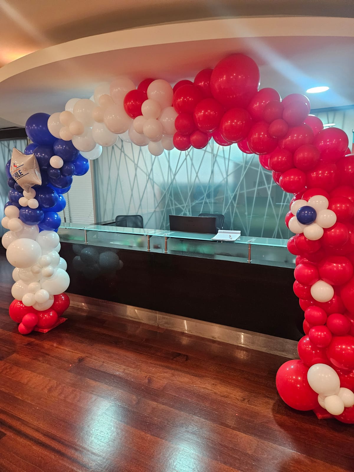 Arco tricolor de globos para Fiestas Patrias en la recepción de una oficina